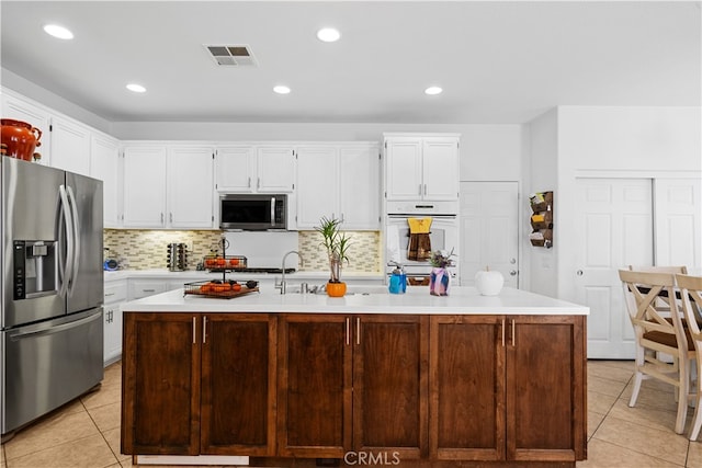 kitchen with light tile patterned floors, stainless steel appliances, visible vents, white cabinetry, and light countertops