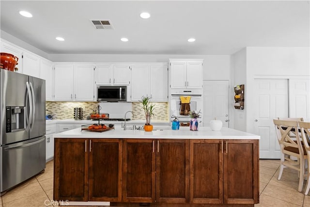 11819 La Costa Ct, Yucaipa, CA 92399 - kitchen featuring appliances with stainless steel finishes, light tile patterned floors, light countertops, white cabinetry, and backsplash