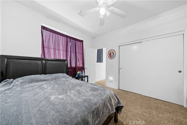 carpeted bedroom with ceiling fan and a closet