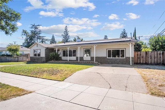 ranch-style home featuring solar panels and a front lawn