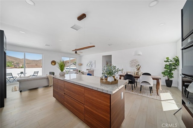 kitchen with a water and mountain view, pendant lighting, light wood-type flooring, and a kitchen island