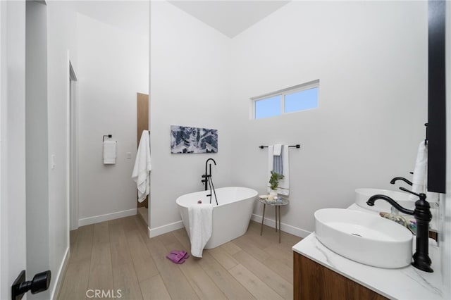 bathroom featuring a tub to relax in, wood-type flooring, and vanity