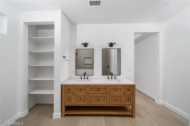 bathroom featuring hardwood / wood-style floors, vanity, and built in shelves