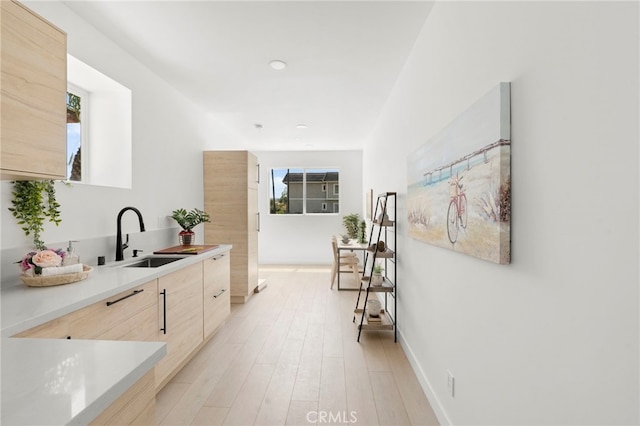 interior space featuring light wood-type flooring, light brown cabinetry, and sink