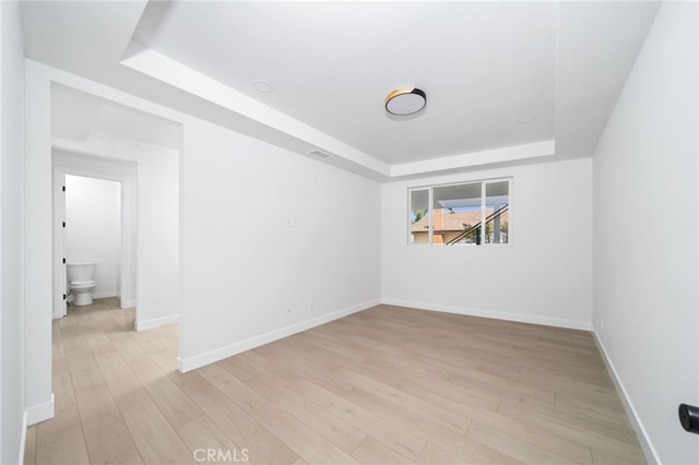 spare room with light hardwood / wood-style floors and a tray ceiling