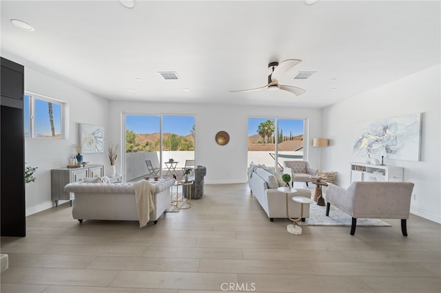 living room featuring ceiling fan, light hardwood / wood-style flooring, and plenty of natural light