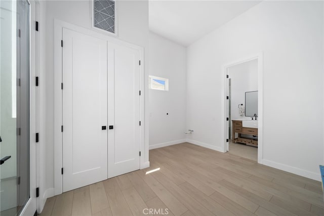 unfurnished bedroom featuring a closet, sink, and light hardwood / wood-style flooring