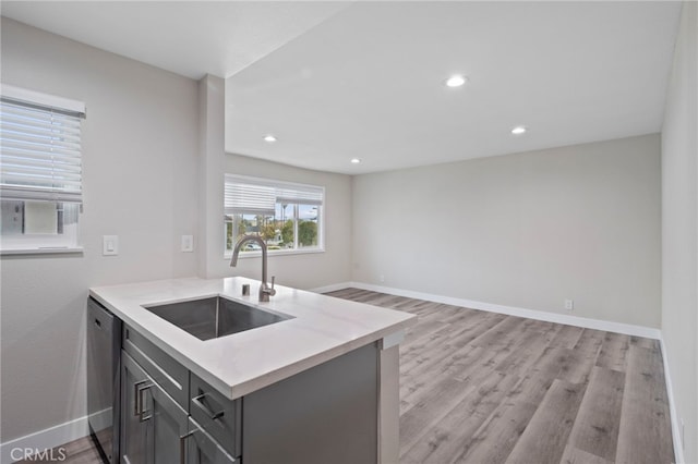 kitchen with light wood-type flooring, stainless steel dishwasher, sink, and kitchen peninsula