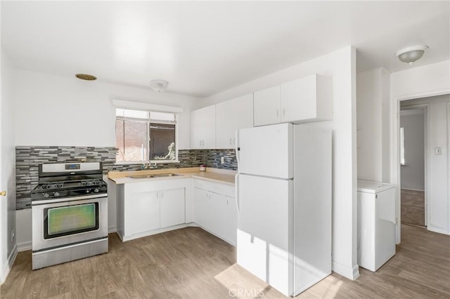 kitchen featuring white cabinetry, stainless steel gas stove, tasteful backsplash, white fridge, and light hardwood / wood-style floors