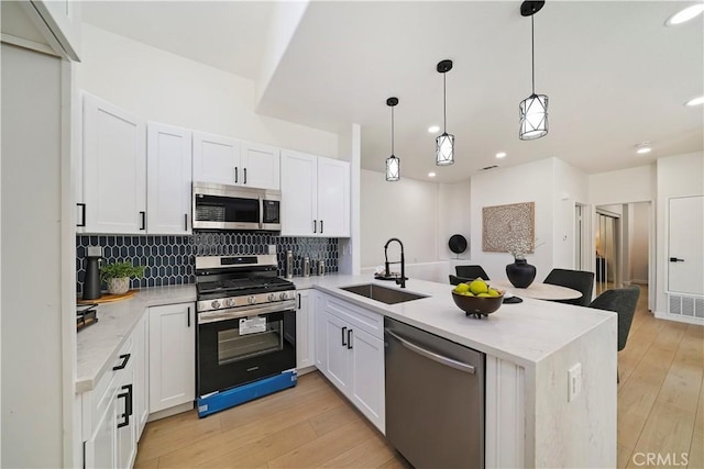 kitchen with kitchen peninsula, pendant lighting, stainless steel appliances, and light hardwood / wood-style flooring