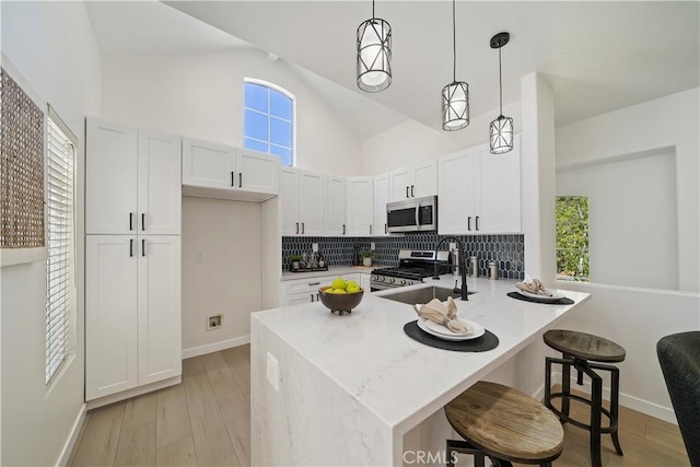 kitchen featuring sink, kitchen peninsula, decorative light fixtures, white cabinets, and appliances with stainless steel finishes