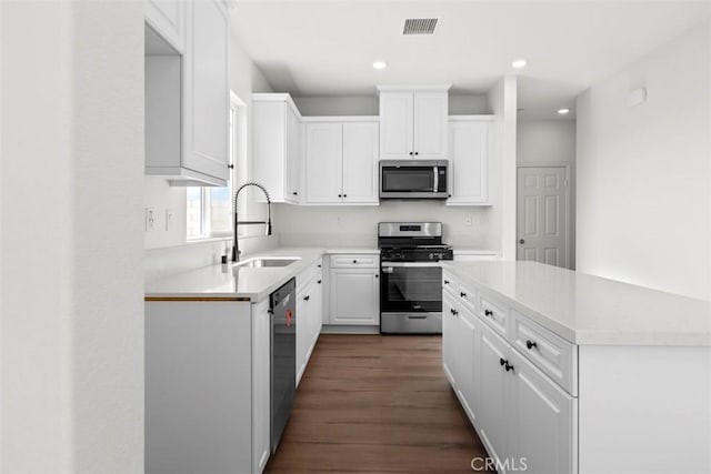 kitchen with stainless steel appliances, dark hardwood / wood-style flooring, white cabinetry, and sink