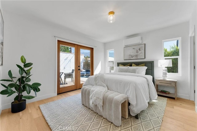 bedroom featuring french doors, light wood-type flooring, access to outside, and a wall unit AC