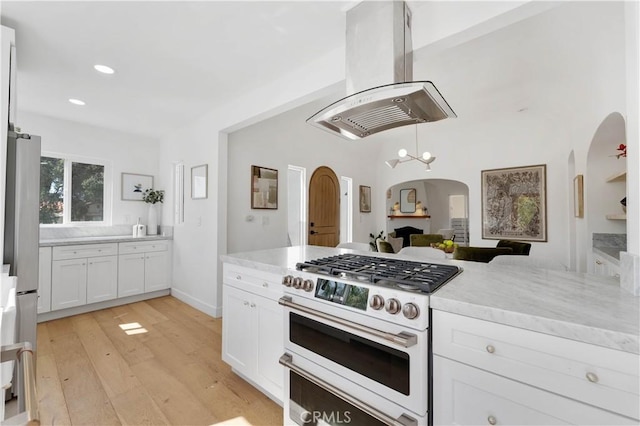 kitchen with island range hood, high end white range oven, ceiling fan, light hardwood / wood-style flooring, and white cabinetry