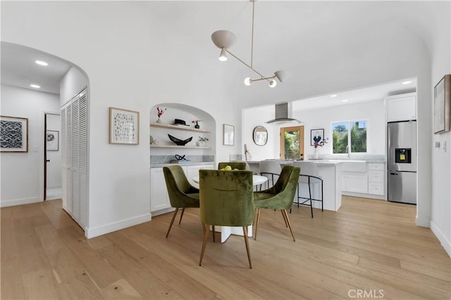 dining space with built in shelves, sink, a chandelier, and light hardwood / wood-style flooring