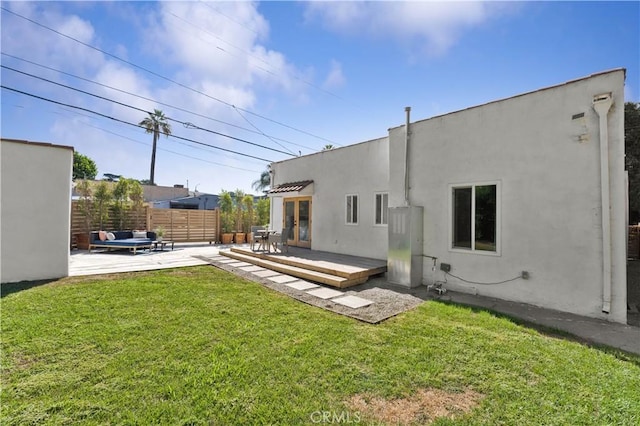 rear view of property featuring a lawn, a wooden deck, and a patio