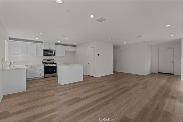 kitchen with white cabinets, stainless steel appliances, light hardwood / wood-style floors, and sink