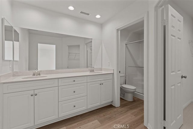 bathroom with hardwood / wood-style flooring, vanity, toilet, and a shower with shower door