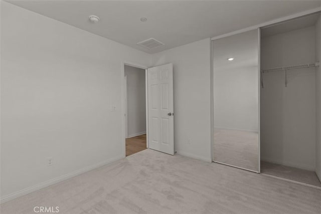 unfurnished bedroom featuring light carpet and a closet