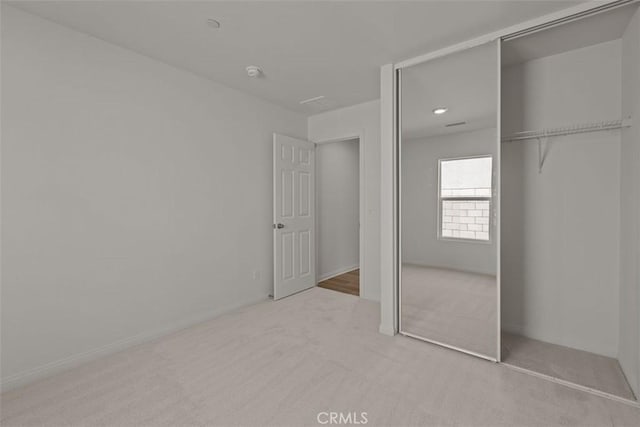 unfurnished bedroom featuring light carpet and a closet