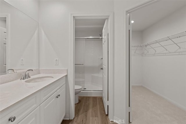 bathroom featuring vanity, toilet, wood-type flooring, and walk in shower