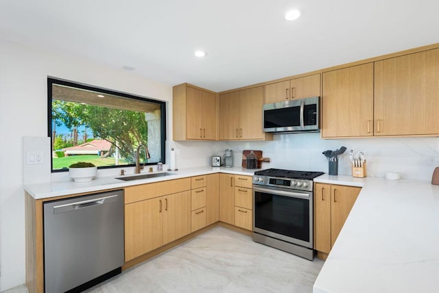 kitchen with light brown cabinetry, appliances with stainless steel finishes, sink, and backsplash