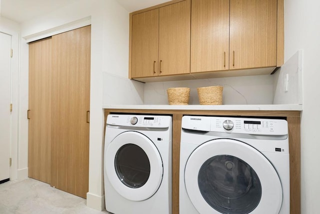 laundry area with separate washer and dryer and cabinets