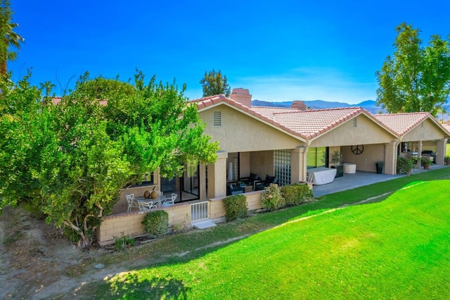 back of property with a patio, a mountain view, and a lawn