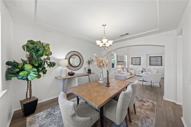 dining room with dark hardwood / wood-style floors and an inviting chandelier