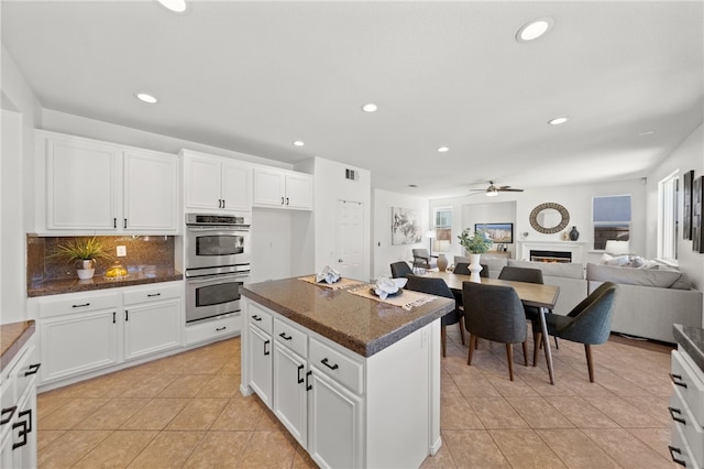 kitchen with white cabinets, stainless steel double oven, and ceiling fan