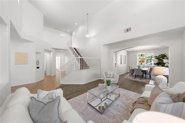 living room with hardwood / wood-style flooring, a high ceiling, and an inviting chandelier