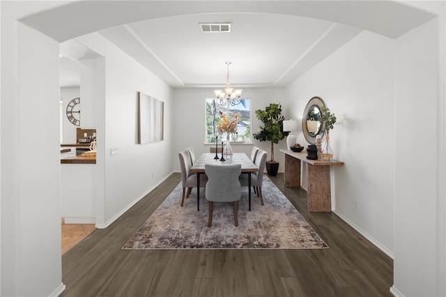 dining area with dark hardwood / wood-style flooring and an inviting chandelier