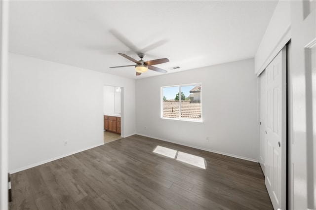 unfurnished bedroom with ceiling fan, dark wood-type flooring, and a closet