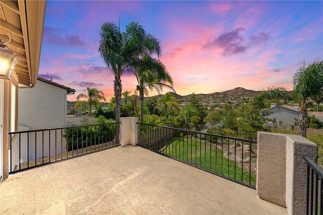 patio terrace at dusk featuring a mountain view and a balcony