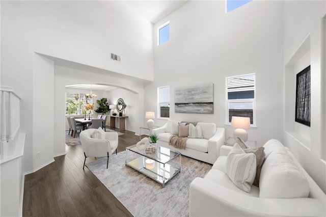 living room featuring hardwood / wood-style flooring, a towering ceiling, and an inviting chandelier