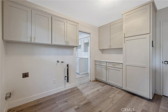 laundry room with cabinets, electric dryer hookup, light hardwood / wood-style flooring, and washer hookup