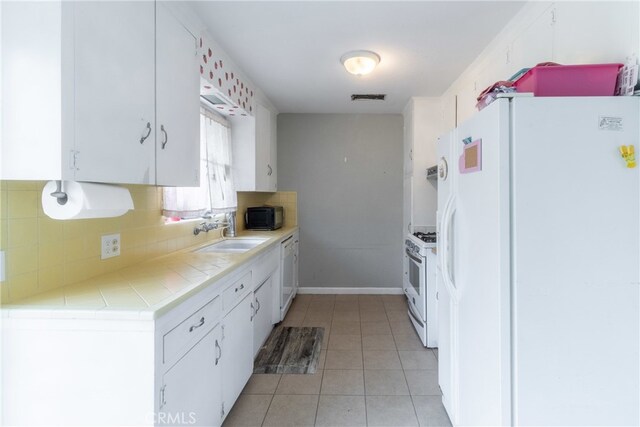 kitchen featuring light tile patterned flooring, tasteful backsplash, white cabinets, white appliances, and sink