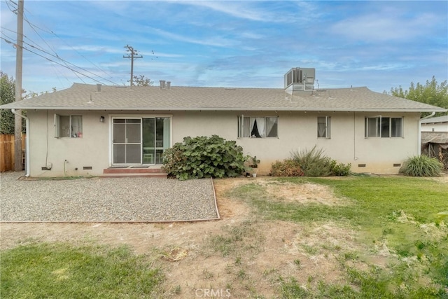 rear view of property featuring a lawn and cooling unit