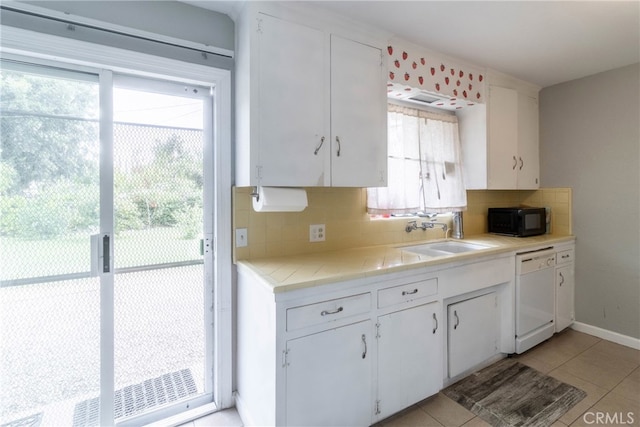 kitchen with dishwasher, tasteful backsplash, sink, white cabinetry, and light tile patterned floors