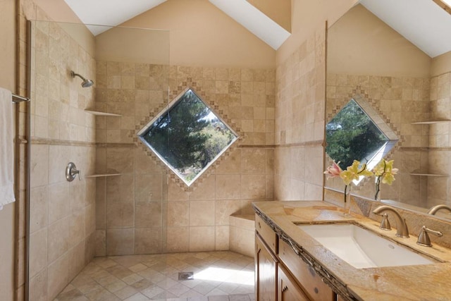 bathroom featuring tile walls, tiled shower, vanity, and lofted ceiling