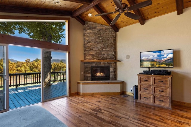 unfurnished living room with vaulted ceiling with beams, wood ceiling, a stone fireplace, and hardwood / wood-style floors