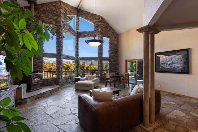 living room with plenty of natural light, beam ceiling, a wood stove, and high vaulted ceiling