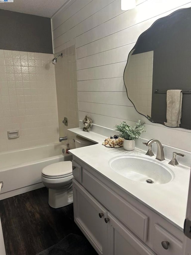 full bathroom with vanity, a textured ceiling, toilet, hardwood / wood-style floors, and tiled shower / bath