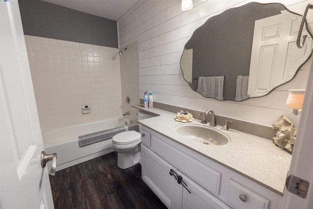 full bathroom with hardwood / wood-style flooring, vanity, toilet, and tiled shower / bath