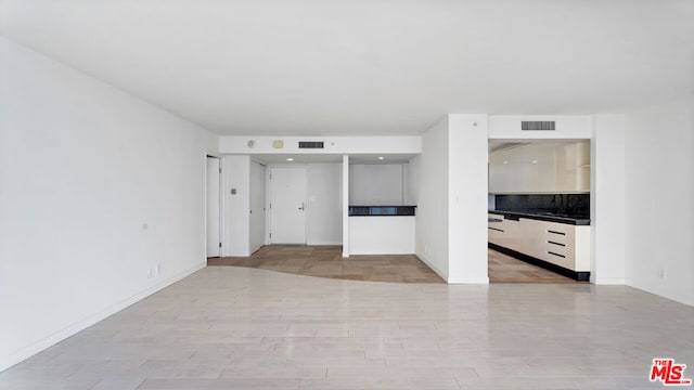 unfurnished living room with sink and light hardwood / wood-style flooring