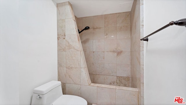 bathroom with a tile shower and toilet