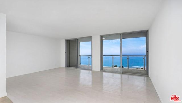 unfurnished room with a water view, light hardwood / wood-style floors, and floor to ceiling windows