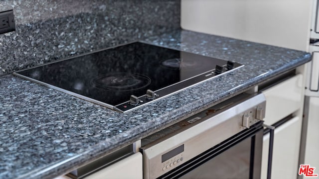 details with black electric stovetop, tasteful backsplash, and oven