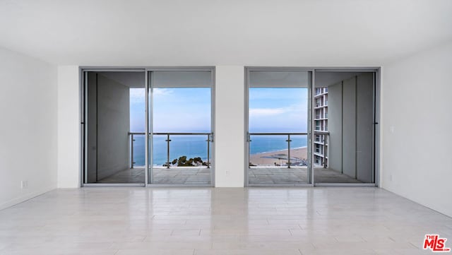 spare room featuring a wall of windows and a water view