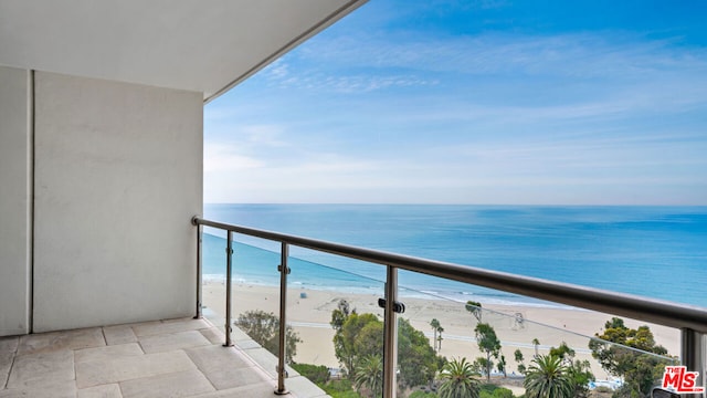 balcony with a water view and a view of the beach